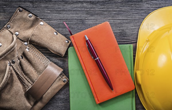 Set of tool belt note-books pen hard hat on wooden board construction concept