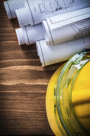 Safety goggles construction drawings and building helmet on wooden background