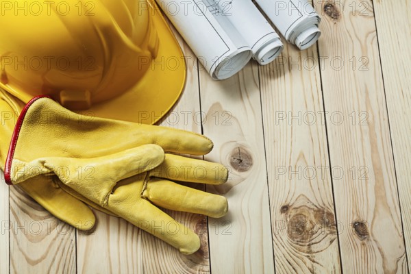 Gloves helmet and construction blueprints on wood