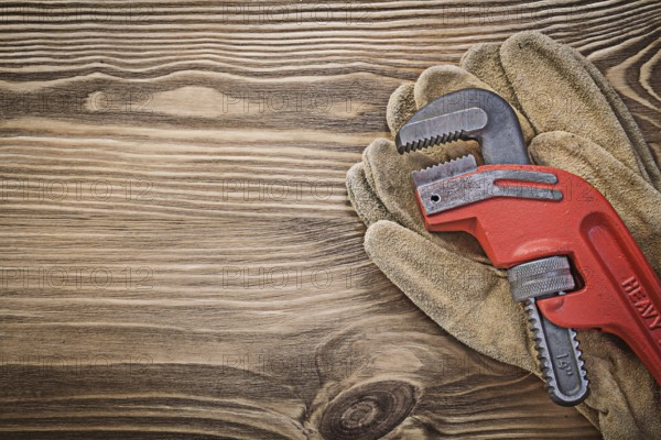 Pair of leather protective gloves monkey wrench on wood board construction concept