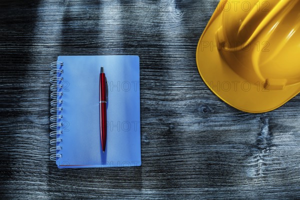 Notepad pen hard hat on wooden board