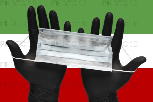 Doctor holds respiratory face mask in hands in black medical gloves on background colors flag of Islamic Republic of Iran. Concept coronavirus quarantine, pandemic outbreak, grippe, airborne diseases