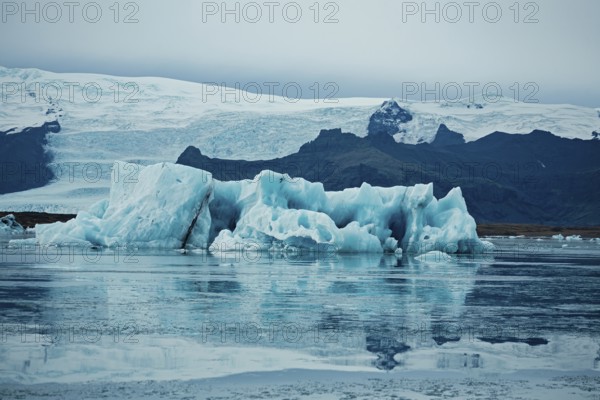 Icy blue icebergs mirrored in calm water amidst a vast glacier and mountainous backdrop, iceberg, glacier, snow, ice rock, ice diamont, glacier lagoon, nature, snow, diamont beach, Iceland