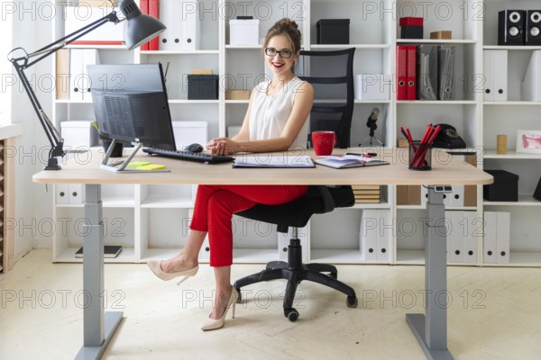 A young girl is sitting at the desk in the office