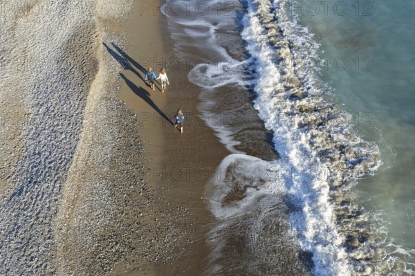 Aerial drone point of view of person walking on sand in a beach. Stormy waves idyllic beach in winter