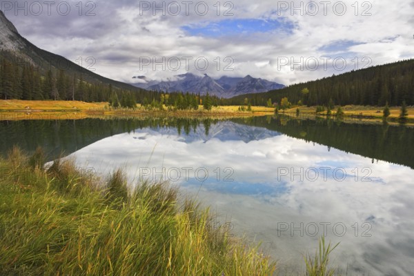 Lake in mountains surrounded by a wood and the cloudy sky