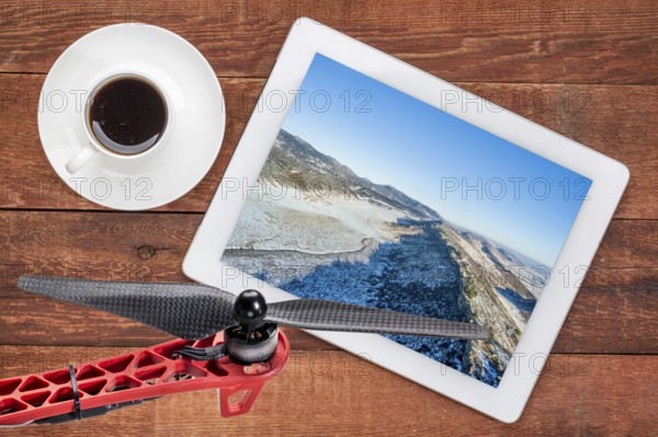 Aerial landscape photography concept - reviewing aerial pictures of a mountain valley in Colorado on a digital tablet with a drone rotor in foreground, screen picture copyright by the photographer