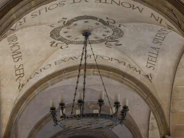 Decorated ceiling with Latin lettering and large chandelier, montserrat, spain