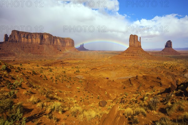 The USA. Monument Valley is unique geological formation. Huge masses of red sandstone - outliers on the Navajo Indian Reservation. Magnificent rainbow across the sky. Concept of photo tourism