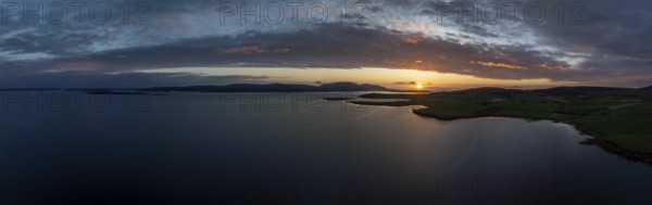 Sunset with cloud band on the coast of Scapa Flow with view to the island of Hoy, drone shot, Orphir, Orkney, Scotland, Great Britain
