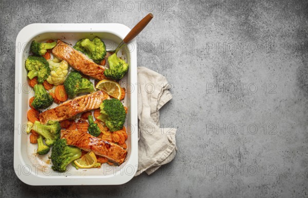 Top view of healthy baked fish salmon steaks, broccoli, cauliflower, carrot in casserole dish on gray stone background. Cooking a delicious low carb dinner, healthy nutrition concept. Space for text, food photography, food photography