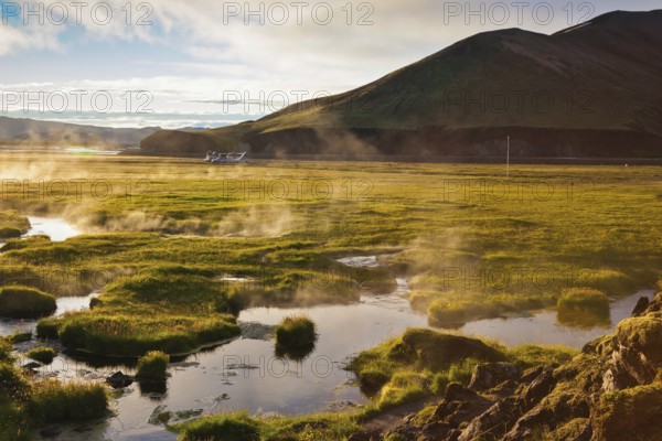 Above the source of thermal water steam rises. White nights in Iceland. Sunrise Park Landmannalaugar