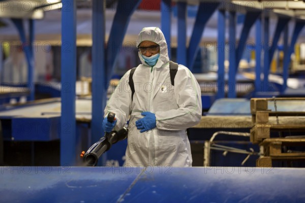 Sofia, Bulgaria - 7 April, 2020: Worker sprays disinfectant outside of ? food market against the spread of coronavirus disease COVID-19