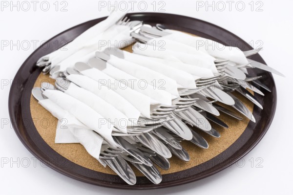 Many forks and knives folded for one person on tray