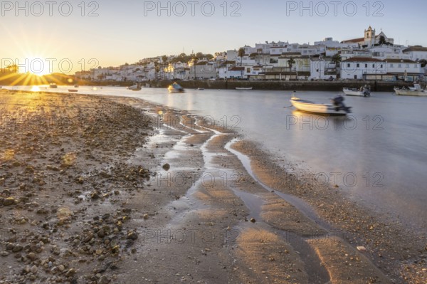 Sunrise with view over a beach and harbour basin at low tide. Panorama picture of a historic old town in the morning, of the village Ferragudo, Portimão, Algarve, Portugal