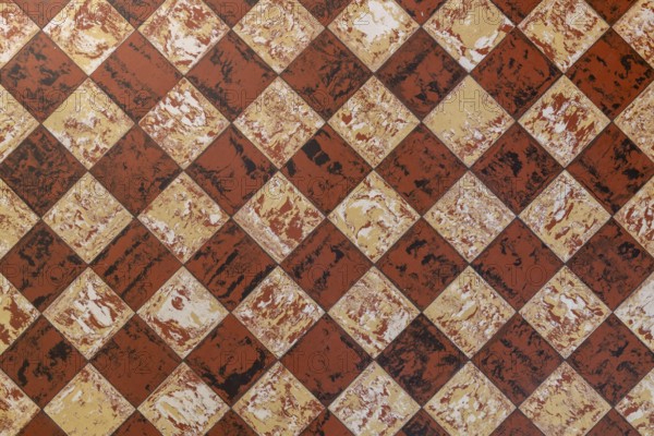Old-fashioned antique brown beige floor tiles in a characteristic old farmhouse in the Netherlands as a full-screen background photo