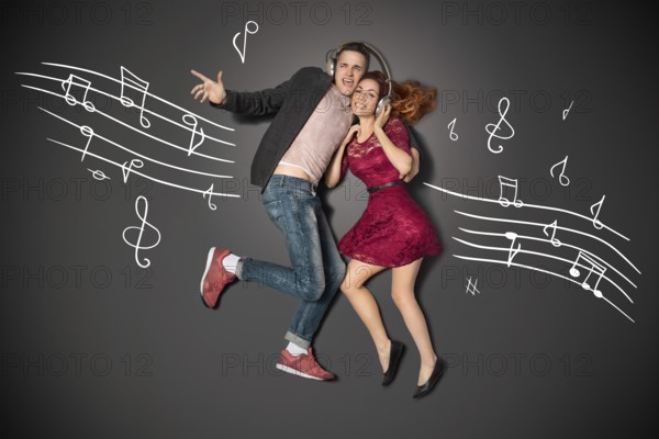 Happy valentines love story concept of a romantic couple sharing headphones and listening to music against chalk drawings background