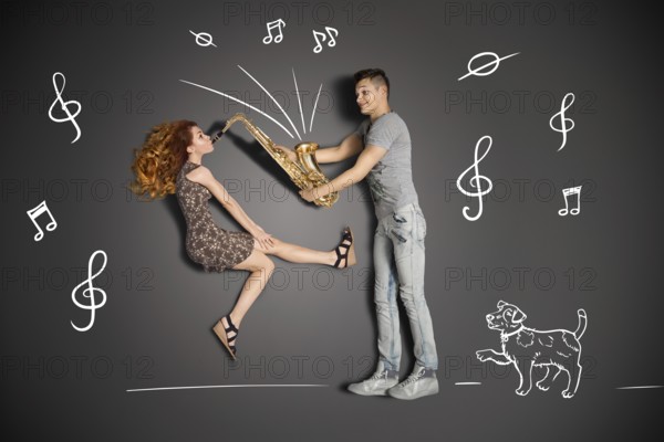 Happy valentines love story concept of a romantic couple against chalk drawings background. Woman playing the saxophone for her boyfriend