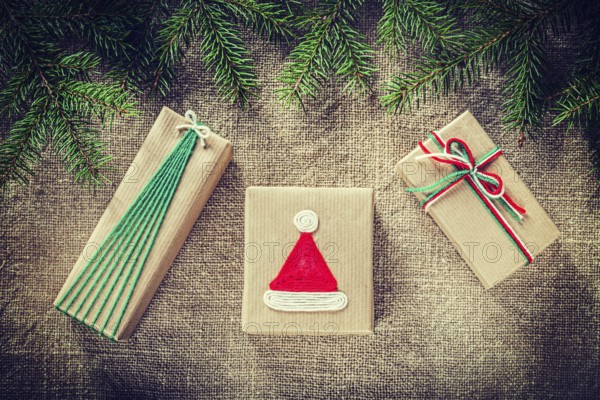 Green pine tree branches handmade gift boxes on burlap background
