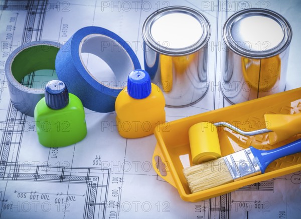 Blueprint with paint brush tray roller cans bottles and household tapes close up image construction concept