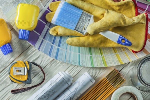 Paint brush in working gloves with any other construction tools on white wood boards