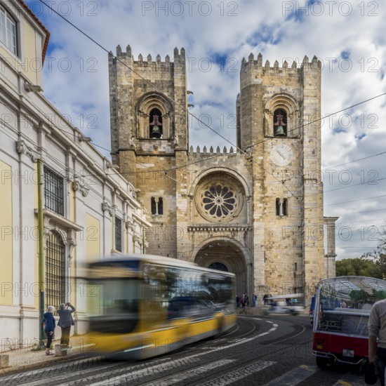 Bus in movement, Historic cathedral with a bus passing by under a cloudy sky in an urban setting, Se Lisbon Cathedral, Lisbon, Portugal