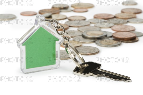 Coins and green house key ring. White isolated studio shot