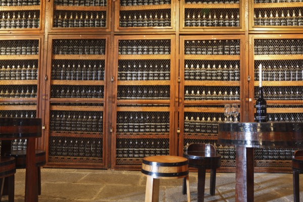 FUNCHAL, MADEIRA - OCTOBER 08, 2011: Museum - repository of expensive vintage wine Madera. Long rows of shelves made of bottles of wine. In the aisle is a round table and stools