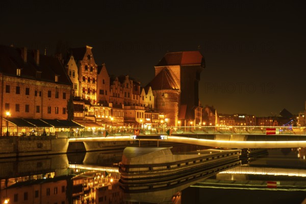Old town in Gdansk at night. The riverside on Granary Island reflection in Moltawa River Cityscape at twilight. Ancient crane at dusk. Visit Gdansk Poland Travel destination. Tourist attraction