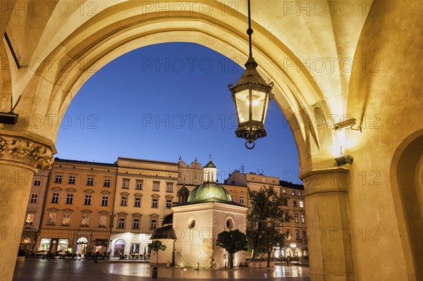 City of Krakow by night in Poland, Ranaissance arch of the Cloth Hall (Sukiennice), St. Adalbert Church and tenement houses at Main Market Square in the Old Town