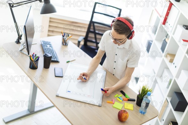 A young man in a white shirt and light jeans is working in a bright office. photo with depth of field