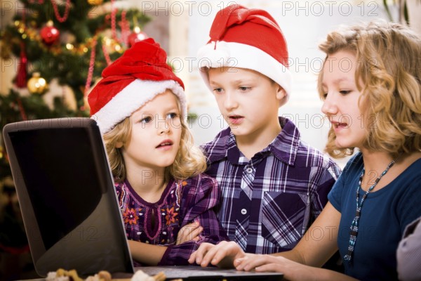 Kids surfing with a laptop at the christmas tree