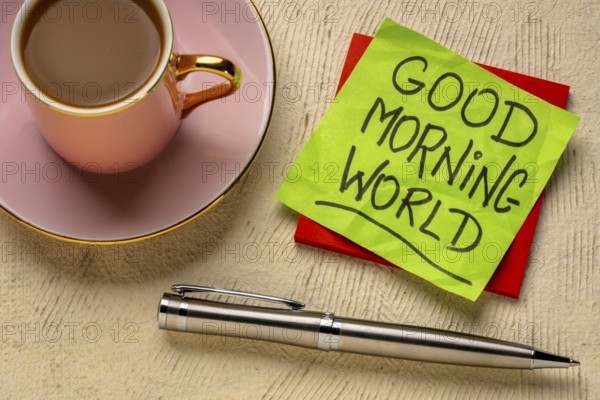 Good Morning world cheerful and positive memo - handwriting on a sticky note with cup of coffee