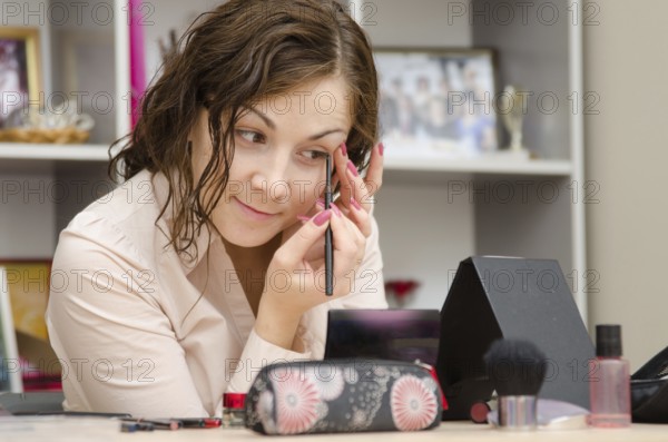 Young girl puts makeup in the office workplace