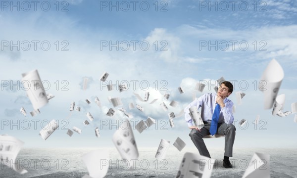 Young businessman sits on an office chair, thoughtful and looking up