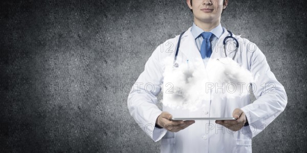 Cropped image of successful young medical industry employee in white sterile suit presenting cloud in his hands while standing against gray background