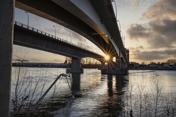 A road or motorway leads through an old historic city gate. Sunset in the evening over the Rhine near Worms, Germany