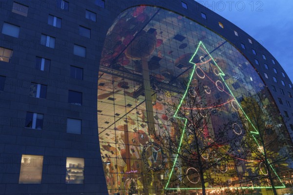 Modern glass façade with large neon-lit Christmas tree decoration at dusk, Rotterdam, Netherlands