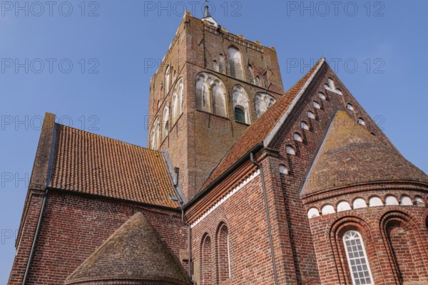 Close-up of the historic church tower and building under a blue sky, krummhörn, east frisia, germany
