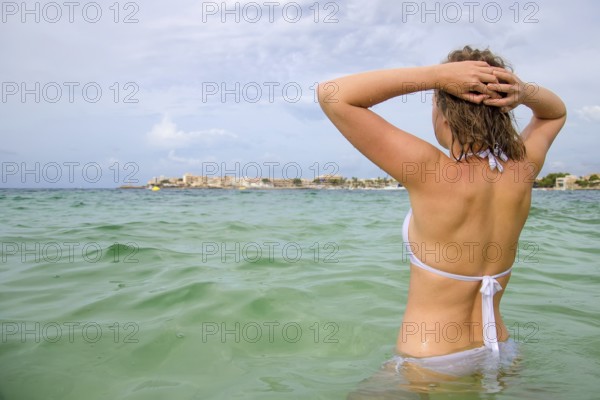 Young woman sunbathes in the sea. Vintage effect