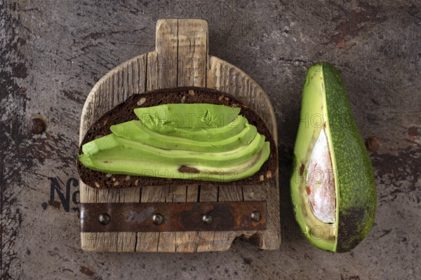 Avocado sandwich on wooden board, vintage iron background