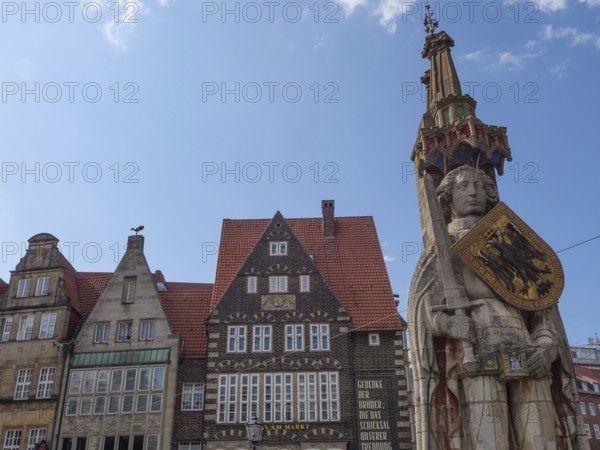 Historic old town with half-timbered houses and a large statue under a blue sky, Bremen, Germany