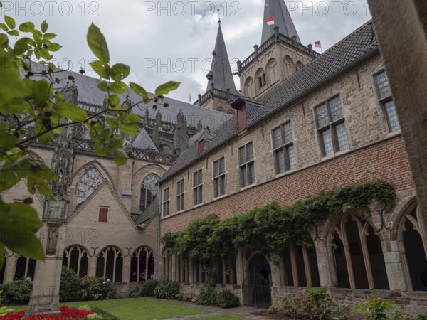 Historic monastery courtyard with Gothic architecture and surrounded by gardens under a cloudy sky, Xanten, North Rhine-Westphalia, Germany