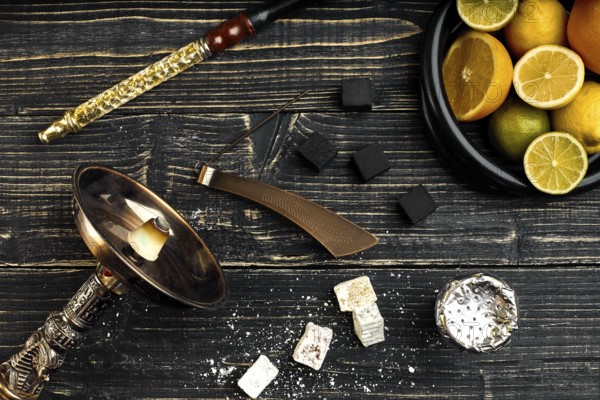 Stylish Smoking hookah and basket with lemon, lime and orange on wooden background. Top view. Flat lay. Copy space. Still life
