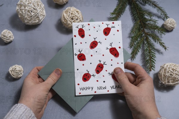 Reindeer fingerprints Sustainable Christmas preparation female hand holding handmade greeting cards with envelope. Inclusive and responsible holiday. Conscious celebration