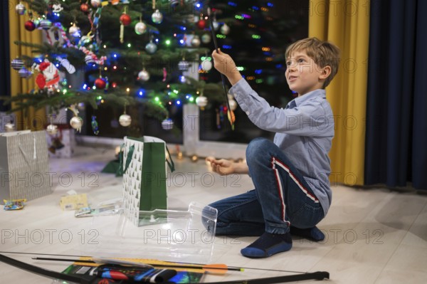 Happy boy opening a Christmas gift and Christmas tree in the background