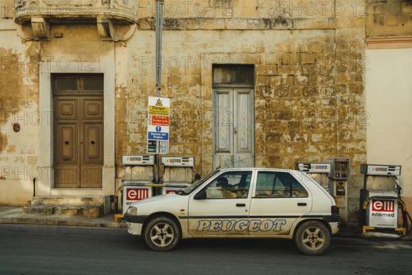 A person refueling a car at a local small gas station located by the side of the road. Self-service refueling. Citadella Gozo, Malta