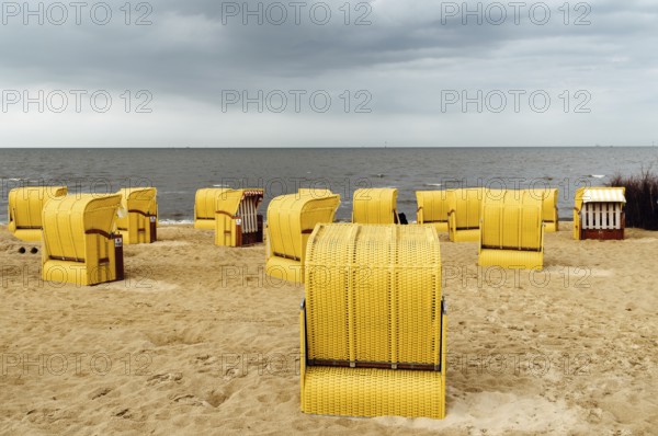 Sandy beach and typical hooded beach chairs in Cuxhaven in the North Sea coast a cloudy day of Summer. Germany