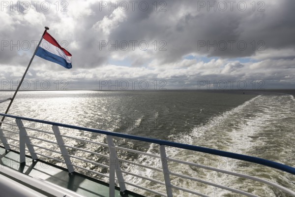 Wadden Sea with Dutch flag and wake as seen from the ferry