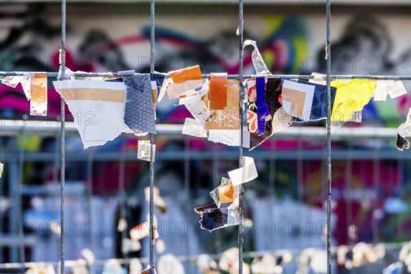 Scraps of paper against a wire fence, symbolising creativity, disorder, protest